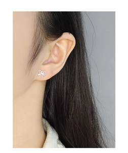 Gros plan d'une boucle d'oreille nœud en argent avec pierre verte sur l'oreille