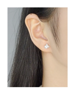 Close-up of elegant silver bow earrings with a white pearl on a model's ear