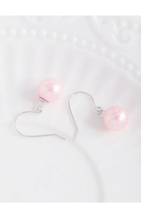 Detail of pink pearl drop earrings with silver hooks on white relief porcelain plate