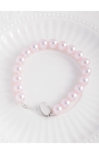 Gros plan du bracelet en perles roses avec fermoir en argent sur plateau blanc