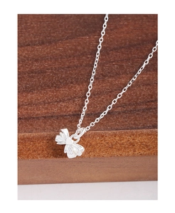 Detail of silver bow pendant with a heart center on a delicate chain necklace