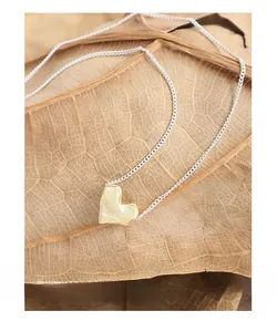 Detailed view of the textured lava heart pendant on a gold and silver necklace