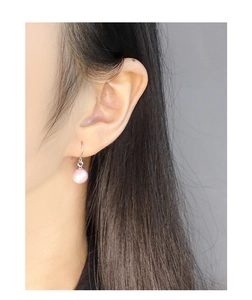 Close-up of elegant pink pearl earrings in S925 silver worn by a model in a side view