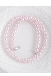 Top view of pink pearl necklace with silver clasp inside a white decorative porcelain plate