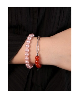 Détail du bracelet en perles roses et chaîne argentée avec perles rouges au poignet