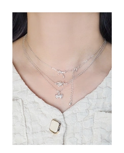 Detailed view of S925 silver bow pendant necklace with adjustable heart charm on model
