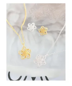 Macro shot of layered hollow flower necklace and stud earrings in gold and silver finish