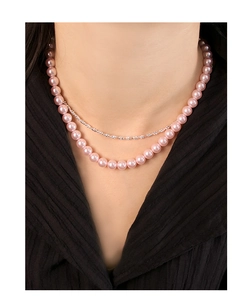 Detail of a layered S925 silver necklace with pink pearls on a model's neck