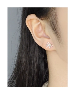 Gros plan d'une boucle d'oreille nœud en argent S925 avec zircon jaune sur l'oreille