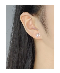 Gros plan d'une boucle d'oreille nœud en argent avec détails en zircon sur l'oreille
