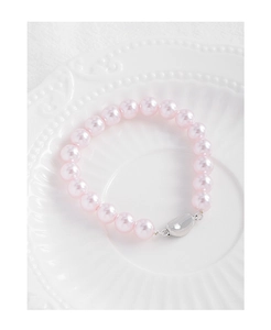 Vue macro du bracelet perles roses avec fermoir cœur argenté sur plat céramique