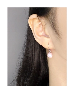 Detail of pink pearl drop earring on model showing delicate luster and silver hook