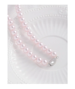 Detailed close-up of pink round pearls and polished silver clasp on white porcelain