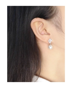 Close-up of S925 silver leaf stud earring with a glossy white pearl on a model's ear