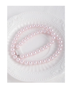 Pink pearl necklace with silver clasp displayed on a white vintage embossed ceramic plate