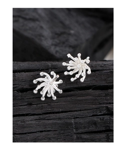 Macro shot of silver fireworks stud earrings with sparkling crystals on dark background