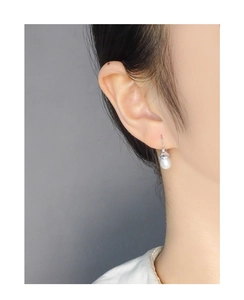 Close-up of elegant S925 silver earring with natural teardrop pearl on female model