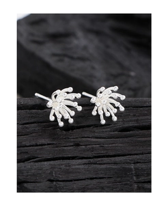 Macro view of S925 sterling silver fireworks earrings on a dark textured wood block
