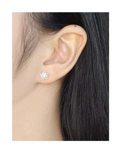 Macro view of double-layer hollow flower stud earring on ear with silver finish