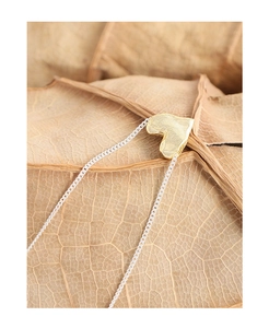 Macro shot of the heart-shaped gold pendant with textured surface on a natural leaf