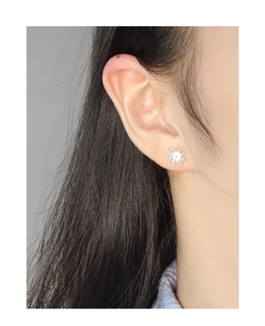 Close-up of S925 silver firework stud earrings worn on ear with minimalist starburst design