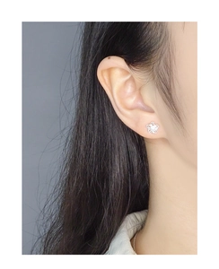 Detail view of silver hollow flower stud earrings on a model showing fine filigree craft