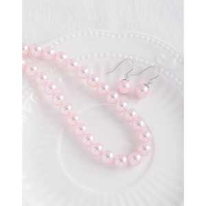 Elegant pink pearl necklace and earrings jewelry set on a white vintage ceramic plate
