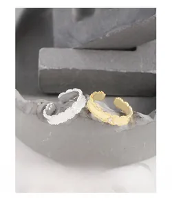 Close-up of adjustable leaf-patterned rings in gold and silver with zircon accents