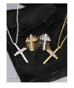 Close-up of twisted cross earrings and necklace with sparkling zircon on dark stone