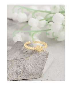 Detail of gold strawberry ring with zircon on stone base and white flowers background