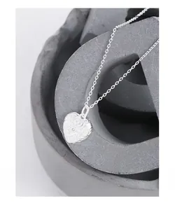 Detailed macro view of S925 sterling silver heart necklace with zircon and relief texture