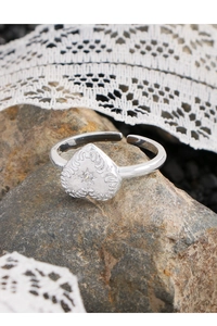 Detailed view of S925 silver heart ring with embossed texture and zircon on rock