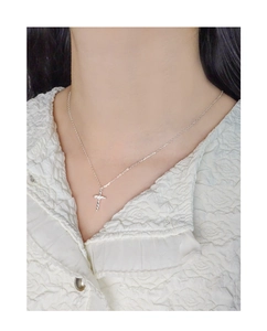Detailed view of S925 sterling silver twisted cross necklace with zircon stones on model