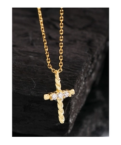 Macro detail of golden twisted texture cross pendant with three inlaid zircons