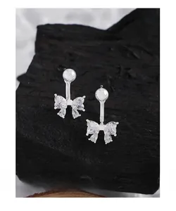 Detailed close-up of S925 sterling silver bow earrings with zircon stones on dark rock