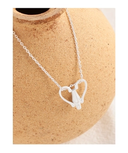 Macro shot of silver S925 heart pendant with ballet shoe detail on a clay pot