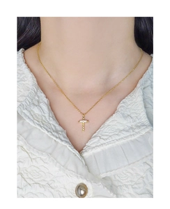 Detailed close-up of a gold twisted cross pendant with sparkling zircons on a neck