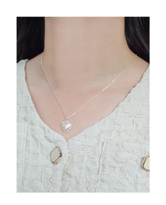 Macro detail of silver S925 heart necklace with vintage vine embossed texture on model