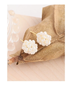 Macro shot of handcrafted cluster pearl earrings on a textured autumn leaf background