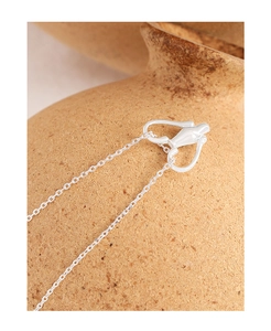 Macro side view of S925 sterling silver heart vase necklace on a brown textured ceramic pot