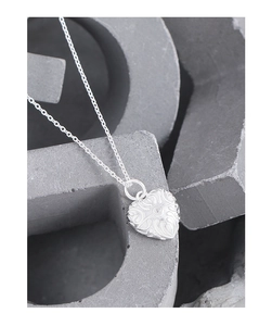 Close-up of S925 silver heart necklace featuring floral embossing and a zircon stone