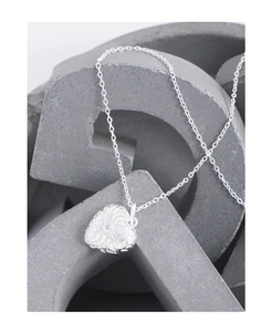 Macro detail of S925 sterling silver heart pendant with baroque floral relief and zircon
