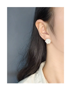 Close-up of cluster pearl stud earrings on model showing elegant floral design