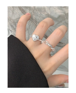 Detailed view of silver heart ring with baroque texture and zircon worn on finger