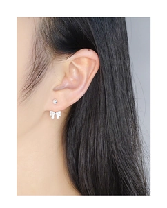 Detailed view of S925 sterling silver bow earrings with sparkling zircon on a model