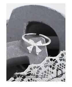 Close-up of polished S925 sterling silver bow ring on a minimalist display