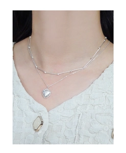 Detail of layered S925 silver necklace with textured heart pendant and bead chain
