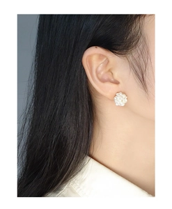 Macro detail of elegant pearl cluster fireworks earrings worn on ear for classic style
