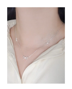 Nahaufnahme der eleganten S925 Silberkette mit drei Schleifenanhängern am Model