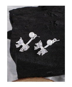 Macro shot of silver S925 bow stud earrings with sparkling cubic zirconia on dark stone